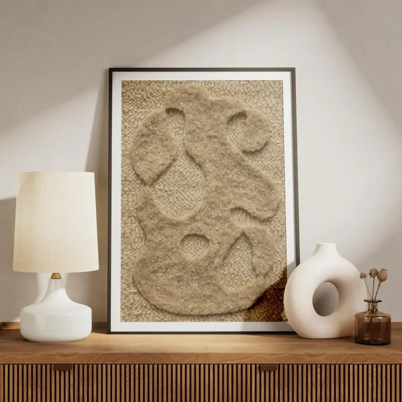affiche abstraite beige avec des formes organiques texturees sur un fond tricote meuble.webp