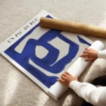 affiche abstraite aux lignes bleues sur fond beige typographie noire en haut et enroule.webp