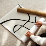 affiche abstraite avec des lignes noires epaisses sur un carre beige clair fond enroule.webp