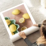 affiche artistique de citrons jaunes sur fond rose certains entiers et certains au sol.webp