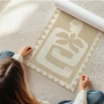 affiche aux couleurs beiges et blanc casse representant une silhouette humaine s en rouleau.webp