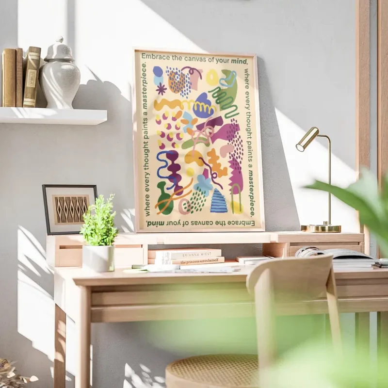 affiche aux formes abstraites et colorees sur fond jaune clair texte vert sur le bureau.webp