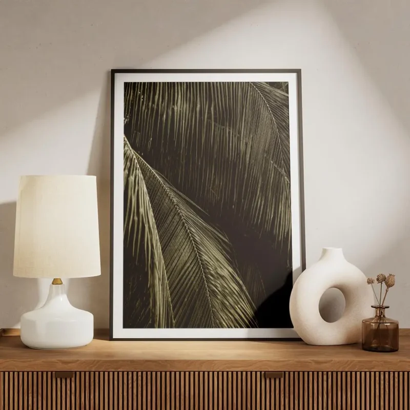 affiche aux teintes sombres representant des feuilles de palmier avec un jeu de meuble.webp