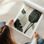 affiche avec de grandes feuilles de bananier vert fonce et blanc casse sur un fo en rouleau.webp