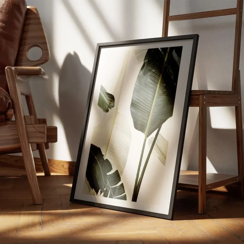 affiche avec de grandes feuilles de bananier vert fonce et blanc casse sur un fo encadre.webp