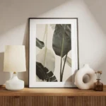 affiche avec de grandes feuilles de bananier vert fonce et blanc casse sur un fo meuble.webp