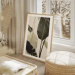 affiche avec de grandes feuilles de bananier vert fonce et blanc casse sur un fo salon beige.webp