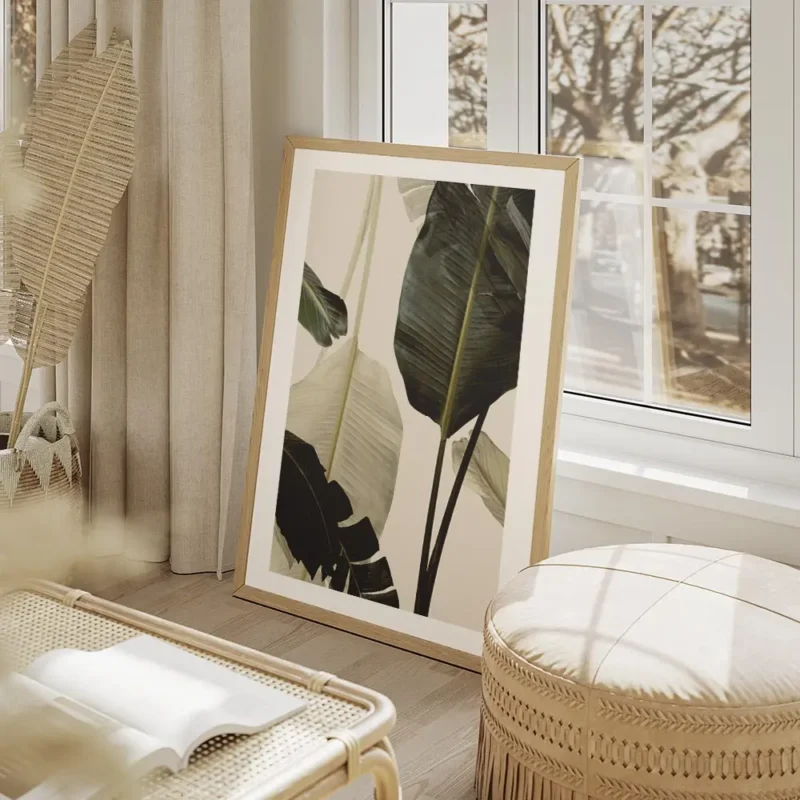 affiche avec de grandes feuilles de bananier vert fonce et blanc casse sur un fo salon beige.webp