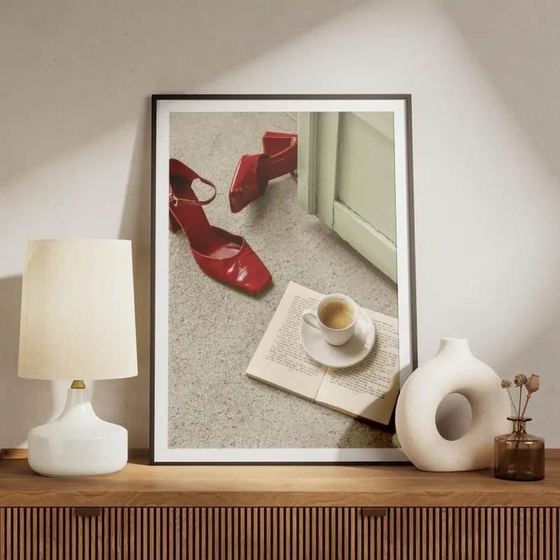 affiche avec des escarpins rouges brillants un livre ouvert et une tasse de cafe meuble.webp