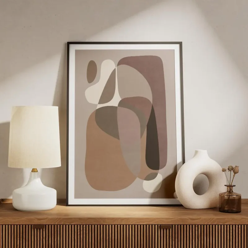 affiche avec des formes courbes et organiques de couleurs beige et marron sur un meuble.webp