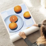 affiche avec des oranges sur une assiette bleue une nappe a carreaux bleus et le au sol.webp