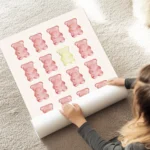 affiche avec des oursons gummy rouges et un jaune au centre disposes en rangees au sol.webp