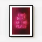 affiche avec enseigne au neon rose fonce this must be the place sur fond sombre avec cadre.webp