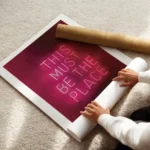 affiche avec enseigne au neon rose fonce this must be the place sur fond sombre enroule.webp