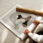 affiche avec formes abstraites grises marron et noires sur fond beige avec un ef enroule.webp