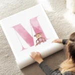 affiche avec la lettre m rose pastel en typographie aquarelle accompagnee dun si au sol.webp