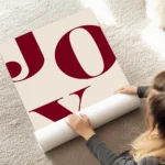 affiche avec le mot joy en grandes lettres rouges typographie serif sur un fond au sol.webp