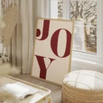 affiche avec le mot joy en grandes lettres rouges typographie serif sur un fond salon beige.webp