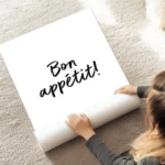 affiche avec le texte bon appetit en calligraphie noire sur fond blanc typograph au sol.webp