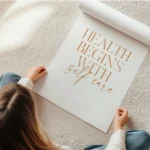 affiche avec le texte health begins with self care en orange sur fond beige clai en rouleau.webp