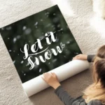 affiche avec le texte let it snow en typographie blanche manuscrite sur un fond au sol.webp