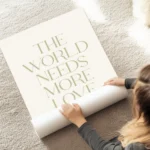 affiche avec le texte the world needs more love en typographie serif verte sur f au sol.webp