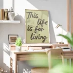 affiche avec les mots this life is for living en marron sur fond vert pale et un bureau.webp