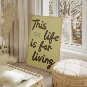 affiche avec les mots this life is for living en marron sur fond vert pale et un salon beige.webp