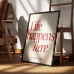 affiche avec linscription life happens here en rouge fonce et lets stay for a wh encadre.webp