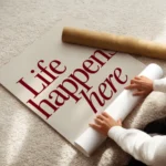 affiche avec linscription life happens here en rouge fonce et lets stay for a wh enroule.webp