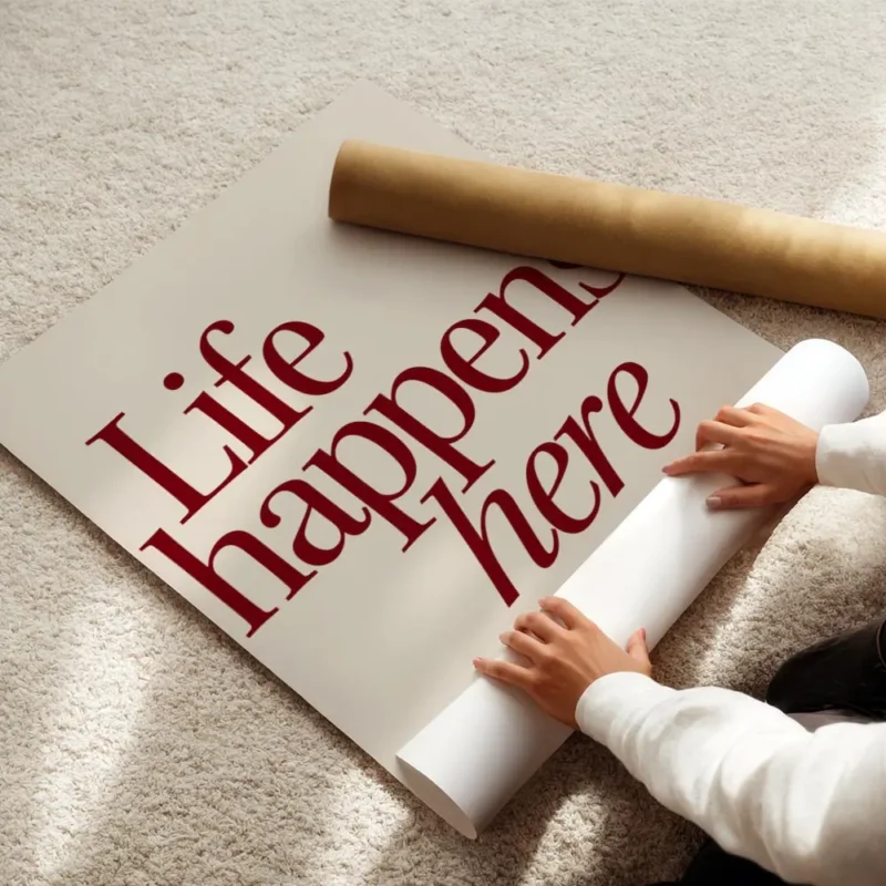 affiche avec linscription life happens here en rouge fonce et lets stay for a wh enroule.webp