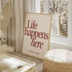 affiche avec linscription life happens here en rouge fonce et lets stay for a wh salon beige.webp