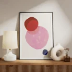 affiche avec trois formes rondes aux teintes vives rouge rose et bleu fonce sur meuble.webp