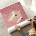 affiche avec trois grues blanches volantes sur un fond rose avec un cercle peche au sol.webp