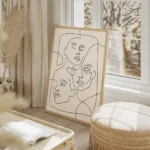 affiche avec trois visages feminins esquisses en lignes noires continues sur un salon beige.webp