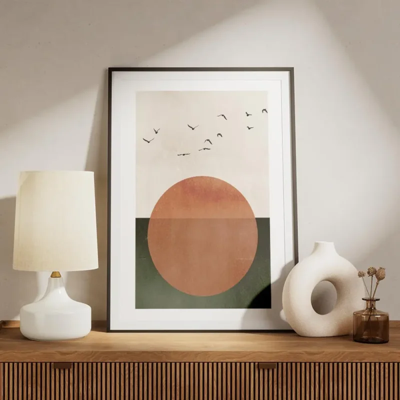 affiche avec un grand soleil orange sur fond beige et vert survole par des oisea meuble.webp