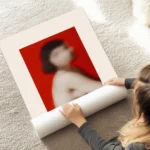 affiche avec un portrait flou dune femme aux cheveux courts sur un fond rouge vi au sol.webp