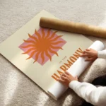 affiche avec un soleil orange sur un carre rose et le texte in the harmony of th enroule.webp
