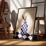 affiche avec un vase a carreaux bleu et blanc et une fleur blanche sur une surfa encadre.webp