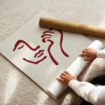 affiche avec un visage abstrait rouge bordeaux et une main sur fond beige clair enroule.webp