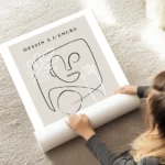 affiche avec un visage abstrait une main et une feuille dessines en noir et blan au sol.webp
