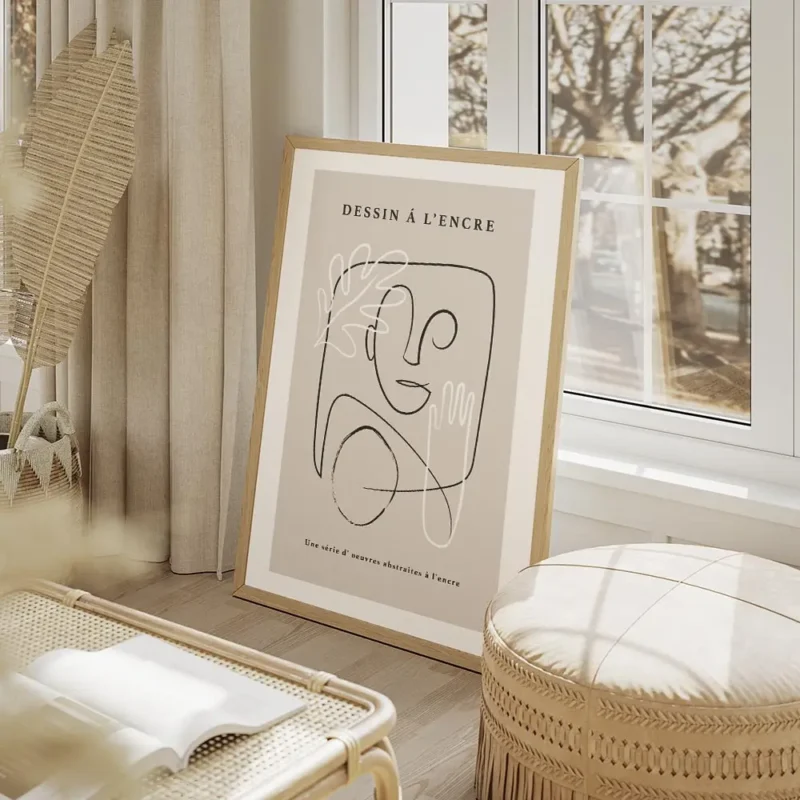 affiche avec un visage abstrait une main et une feuille dessines en noir et blan salon beige.webp