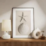 affiche avec une etoile de mer et un coquillage blanc sur du sable pale meuble.webp