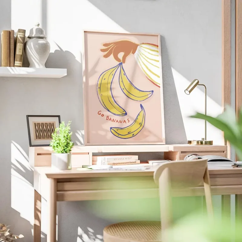 affiche avec une main orange tenant des bananes jaunes et bleues sur fond rose p bureau.webp