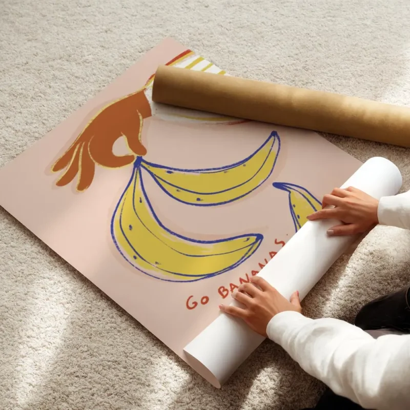 affiche avec une main orange tenant des bananes jaunes et bleues sur fond rose p enroule.webp
