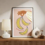 affiche avec une main orange tenant des bananes jaunes et bleues sur fond rose p meuble.webp