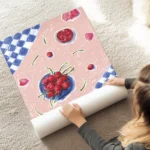 affiche avec une nature morte de cerises rouges et de petales sur une nappe rose au sol.webp