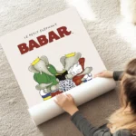 affiche babar et sa famille reine celeste pom flora et alexandre lisant un livre au sol.webp