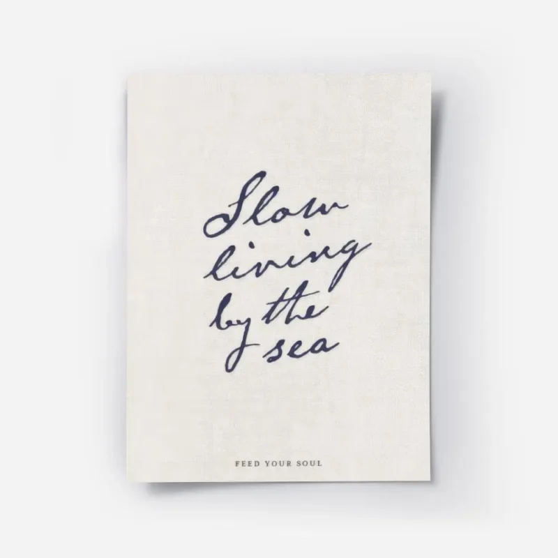 affiche beige avec le texte manuscrit slow living by the sea en bleu fonce et fe.webp