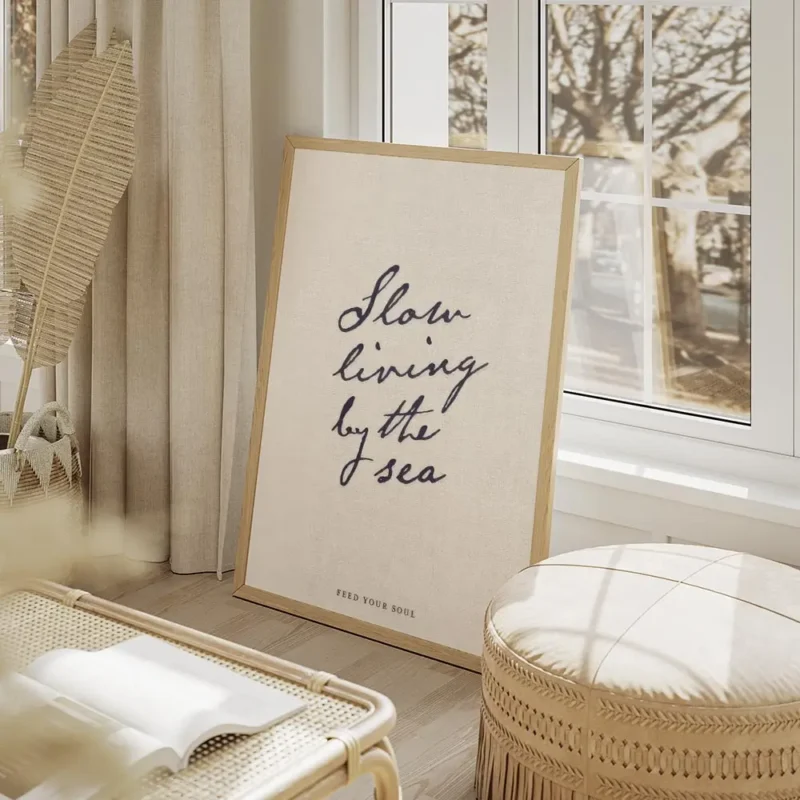 affiche beige avec le texte manuscrit slow living by the sea en bleu fonce et fe salon beige.webp